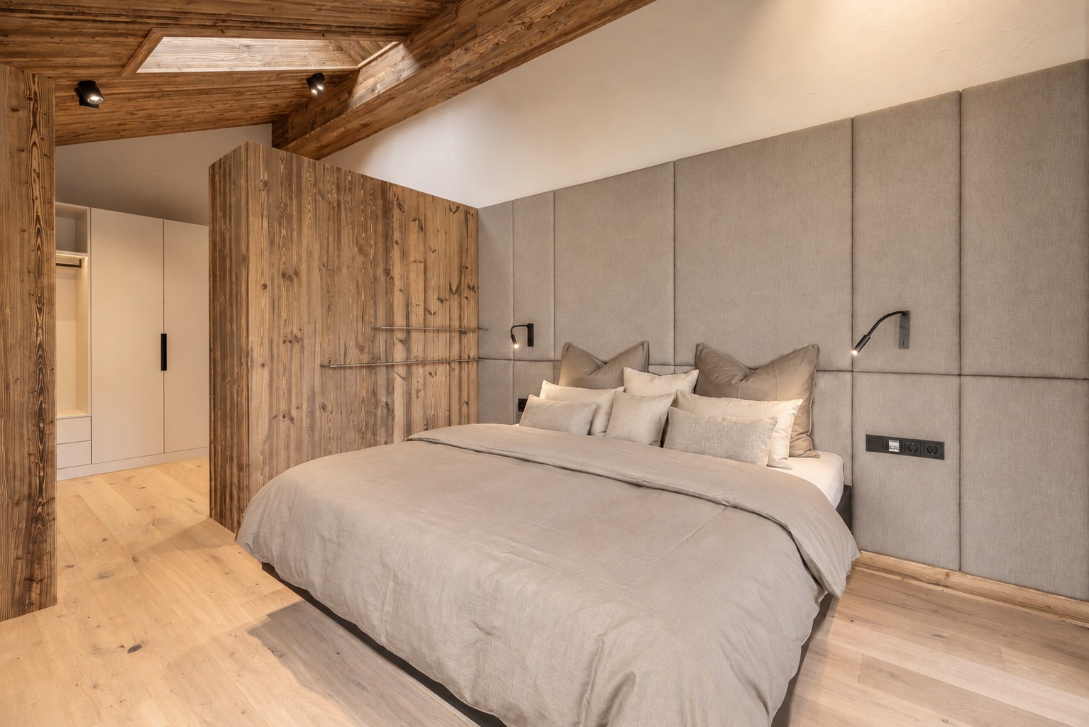 Schlafzimmer mit gepolstertem Kopfteil, grauen Textilien und Holzflächen